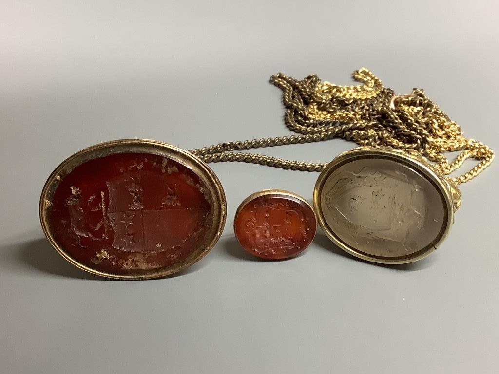 Three assorted 19th century yellow metal overlaid and carnelian set fob seals, two on gilt metal chains, largest 41 mm.
